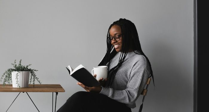 black woman reading with a cup of coffee.jpg.optimal