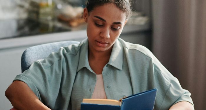 a brown skinned woman reading a book.jpg.optimal