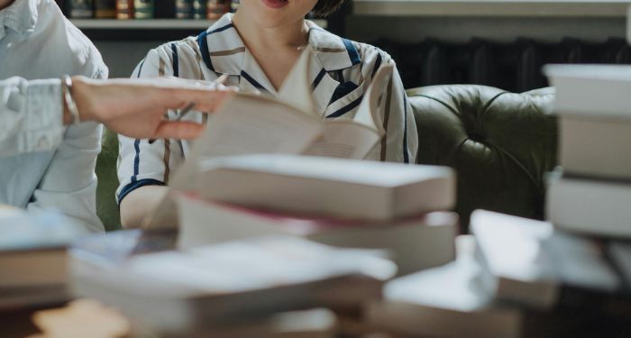 two people looking at books on a desk.jpg.optimal