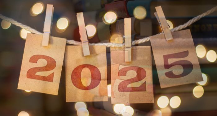 2025 on pieces of brown paper clipped to laundry line with dots of light against semi transparent book stack.jpg.optimal